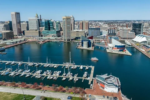 baltimore-md Baltimore Inner Harbor waterfront with docked boats, the National Aquarium, and city buildings in the background.