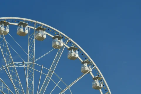 recreation-and-entertainment Partial view of a white Ferris wheel gondola assembly against a clear blue sky at an outdoor amusement attraction