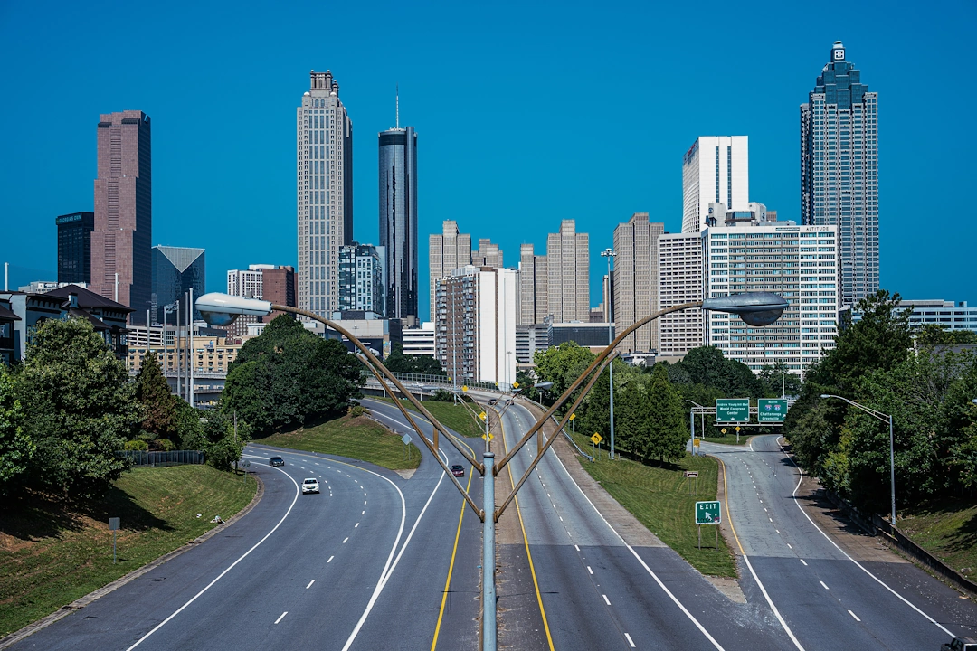 View of downtown Atlanta, Georgia with modern skyscrapers and highways under a bright blue sky.