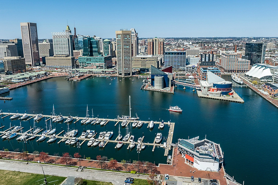 Baltimore Inner Harbor waterfront with docked boats, the National Aquarium, and city buildings in the background.