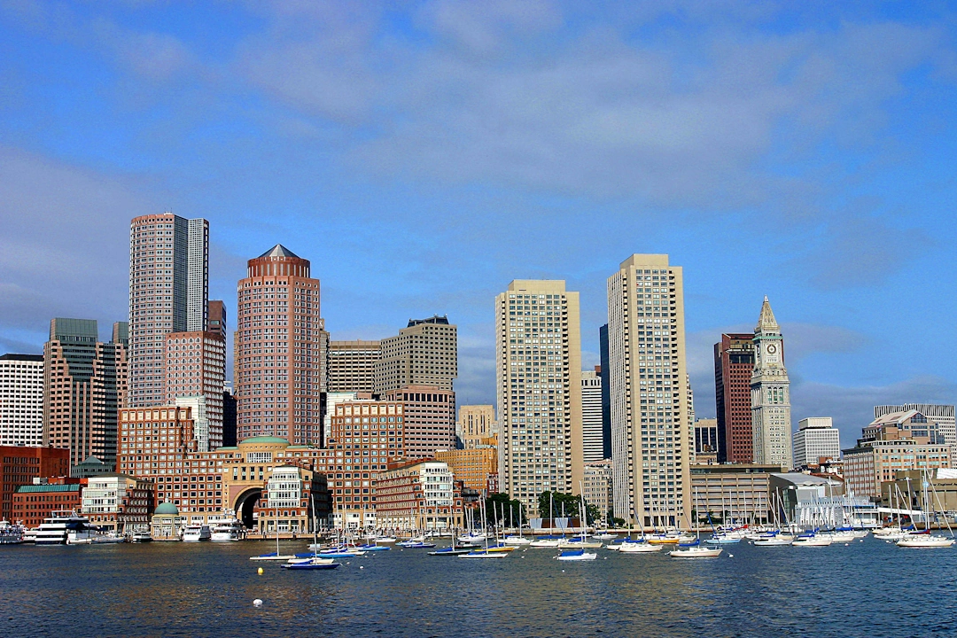 Boston skyline view from the harbor showing boats and a mix of historic and modern skyscrapers.