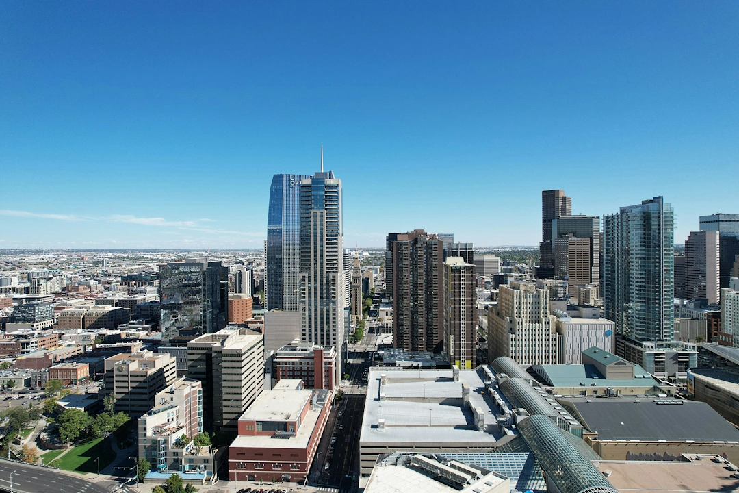Aerial view of downtown Denver, Colorado with modern glass skyscrapers and a clear blue sky.