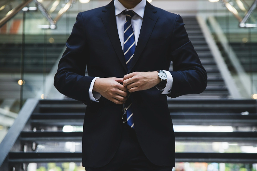 general Business professional in a tailored suit adjusting their jacket in a corporate lobby, representing general services