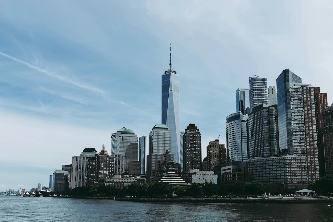 Skyline of Lower Manhattan featuring One World Trade Center and surrounding skyscrapers on a clear day in New York City.