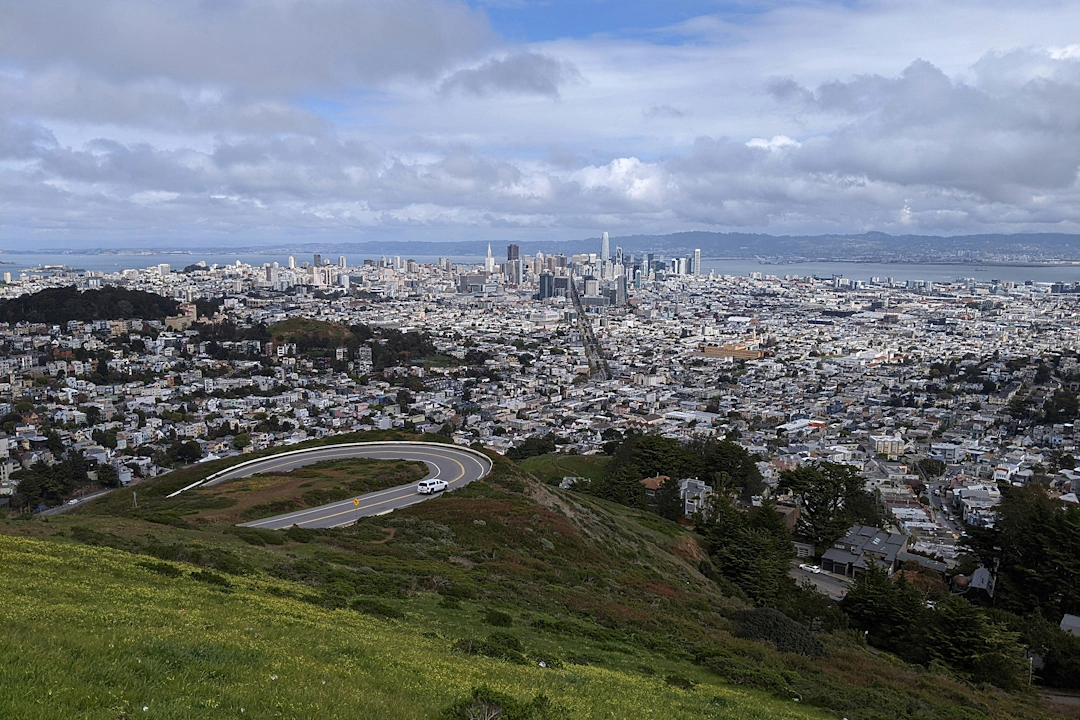 Panoramic view of San Francisco, California from Twin Peaks showing the cityscape and bay under cloudy skies.